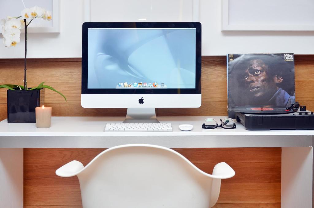 A compact white desk with an iMac, laptop and accessories.