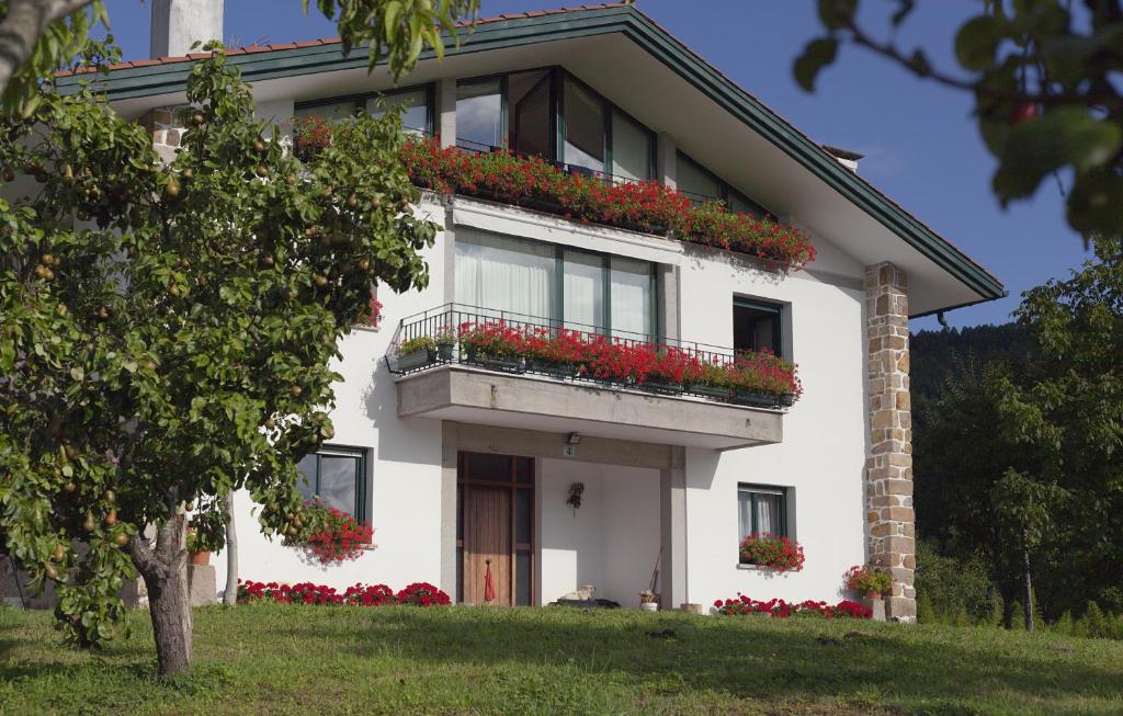 a white house with red flowers on the balcony at Basarte Cottage in Bakio