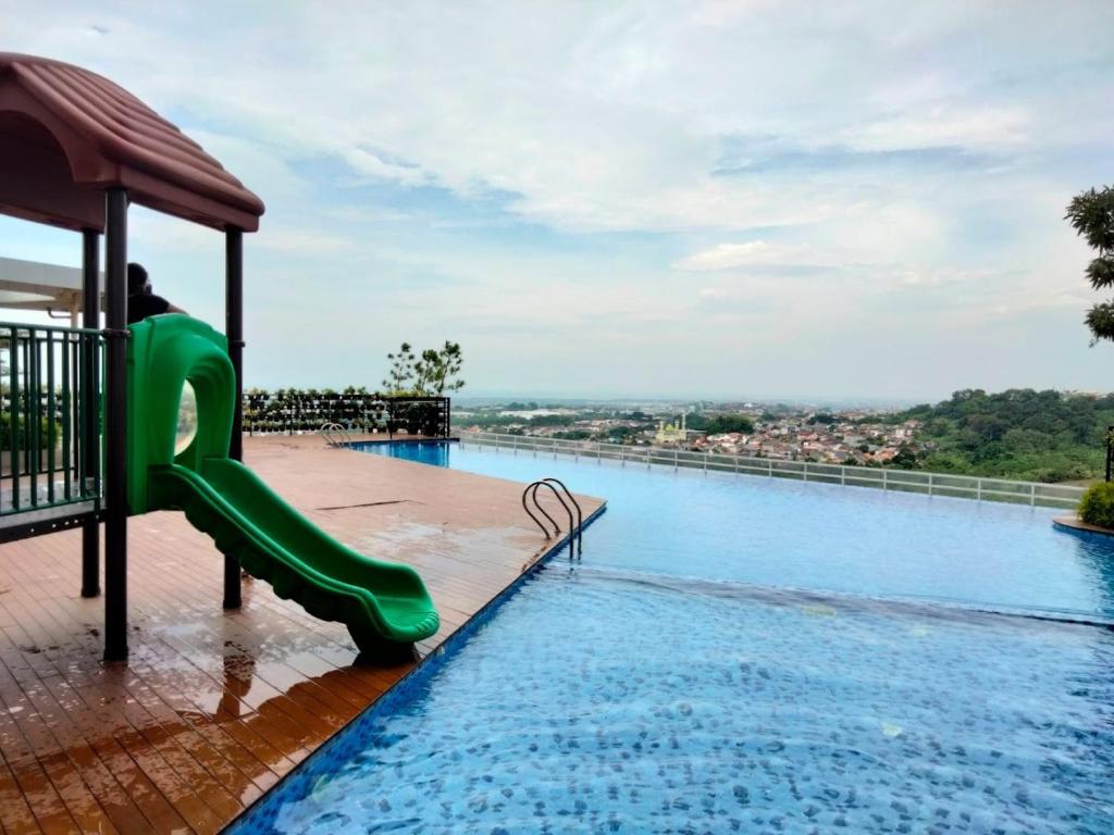 a swimming pool with a green slide and water at Amartha View Apartement in Tambakaji