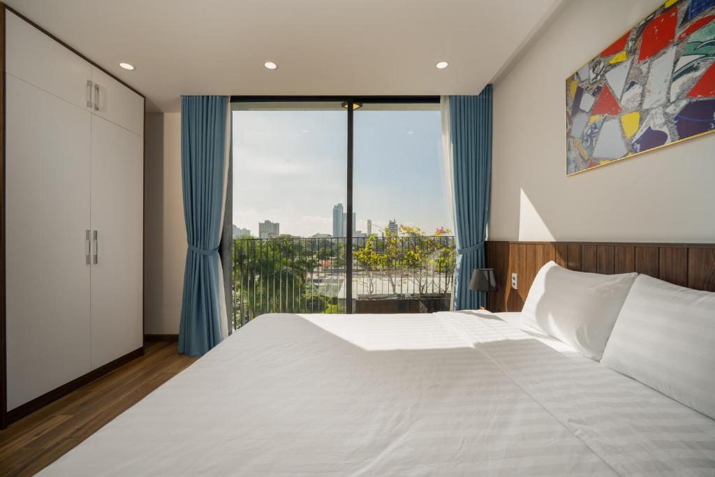 um quarto com uma cama grande e uma janela grande em Maison Vy Anh Hotel & Apartment em Da Nang