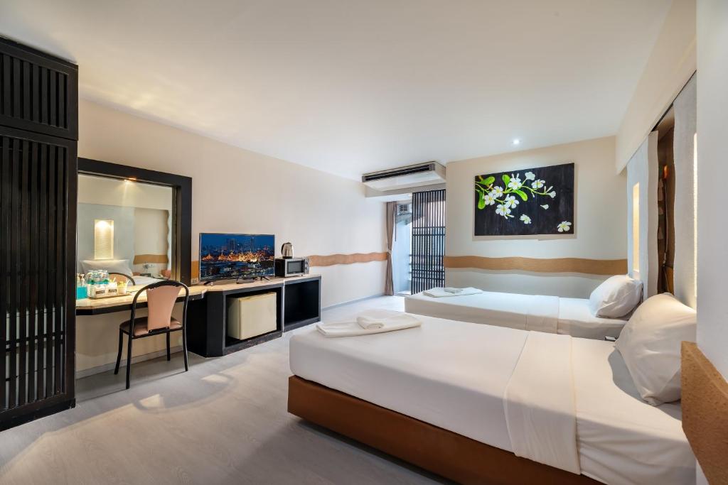 a hotel room with a large bed and a desk at The Legacy Hotel in Nonthaburi
