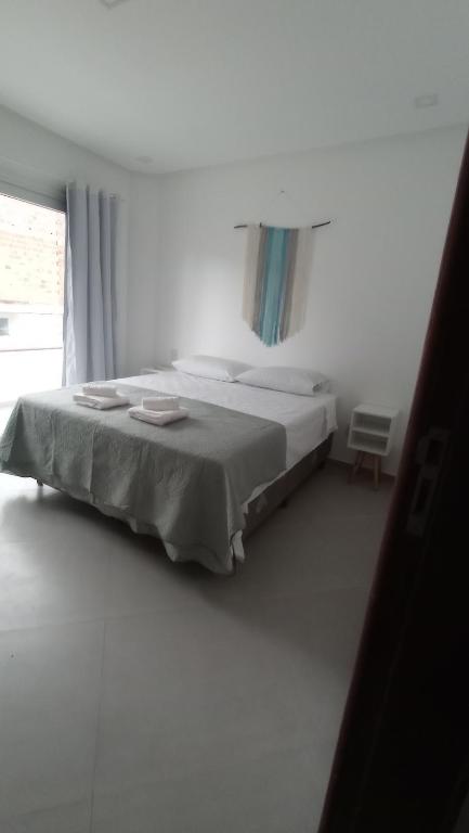 uma cama num quarto branco com uma janela em Apartamento Maresia em Morro de São Paulo