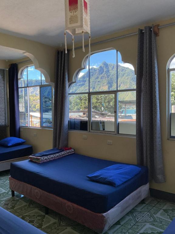 a bedroom with two beds in a room with windows at Mandala’s Hostal in San Pedro La Laguna