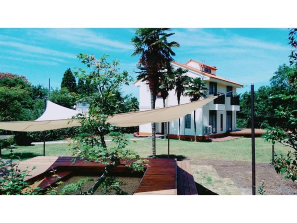 dom z dwoma białymi parasolami przed nim w obiekcie Glamp House DAISEN Garden - Vacation STAY 97255v w mieście Yonago
