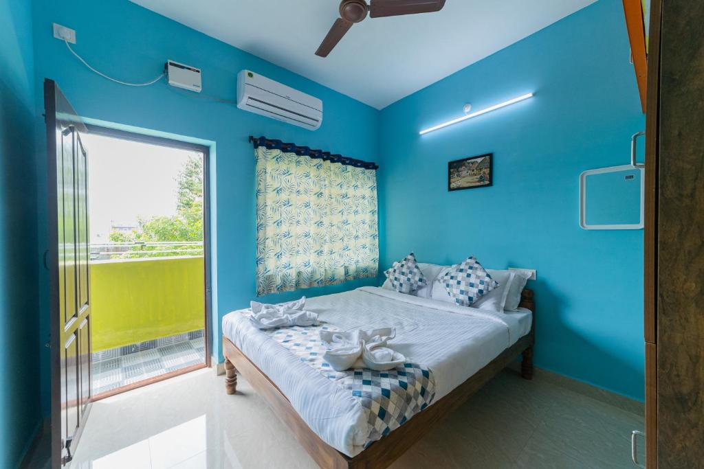 - une chambre bleue avec un lit et une fenêtre dans l'établissement Ameer Homes, à Pondichéry