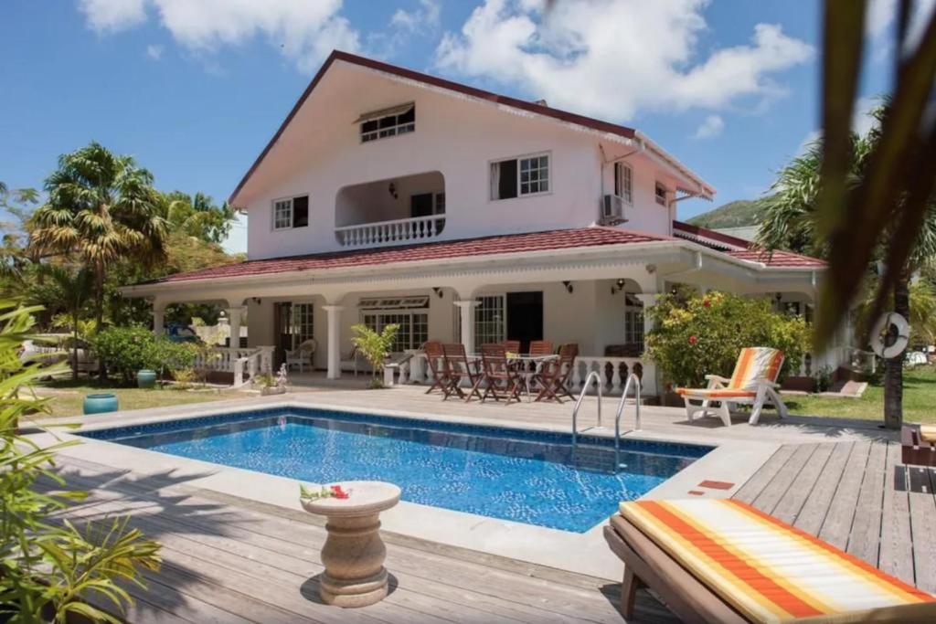 a villa with a swimming pool in front of a house at Villa Confort in Grand'Anse Praslin