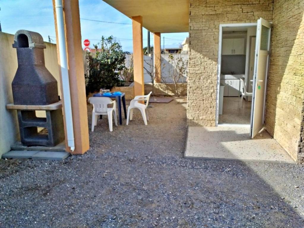 une terrasse avec une cuisinière, une table et des chaises dans l'établissement Appartement ensoleillé avec terrasse et parking, à 2 pas de la plage - Marseillan - FR-1-387-169, à Marseillan