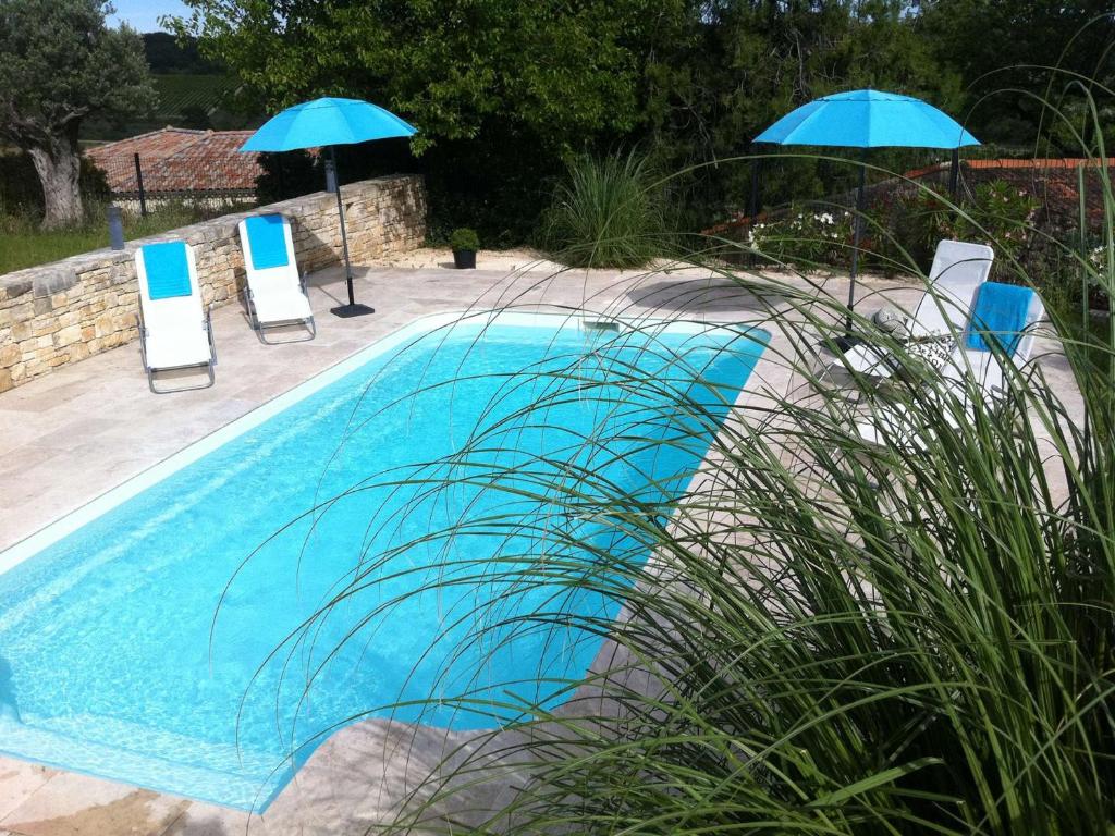 two blue chairs and two umbrellas next to a pool at Maison Vagnas, 4 pièces, 6 personnes - FR-1-382-176 in Vagnas