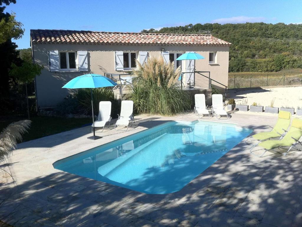 a swimming pool with chairs and umbrellas next to a house at Maison Vagnas, 4 pièces, 6 personnes - FR-1-382-176 in Vagnas