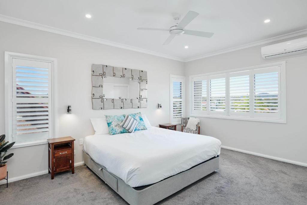a white bedroom with a bed and two windows at Wingham Motel in Wingham