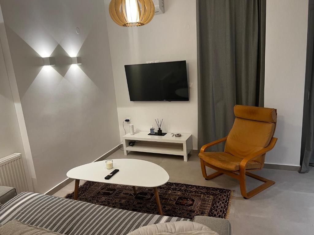 een woonkamer met een tafel, een stoel en een tv bij DISTRiCT 01 - Kalamaria in Thessaloniki
