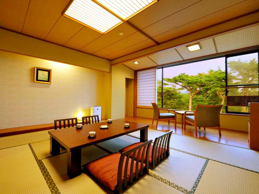 a dining room with a table and chairs and a window at Jodogahama Park Hotel in Miyako