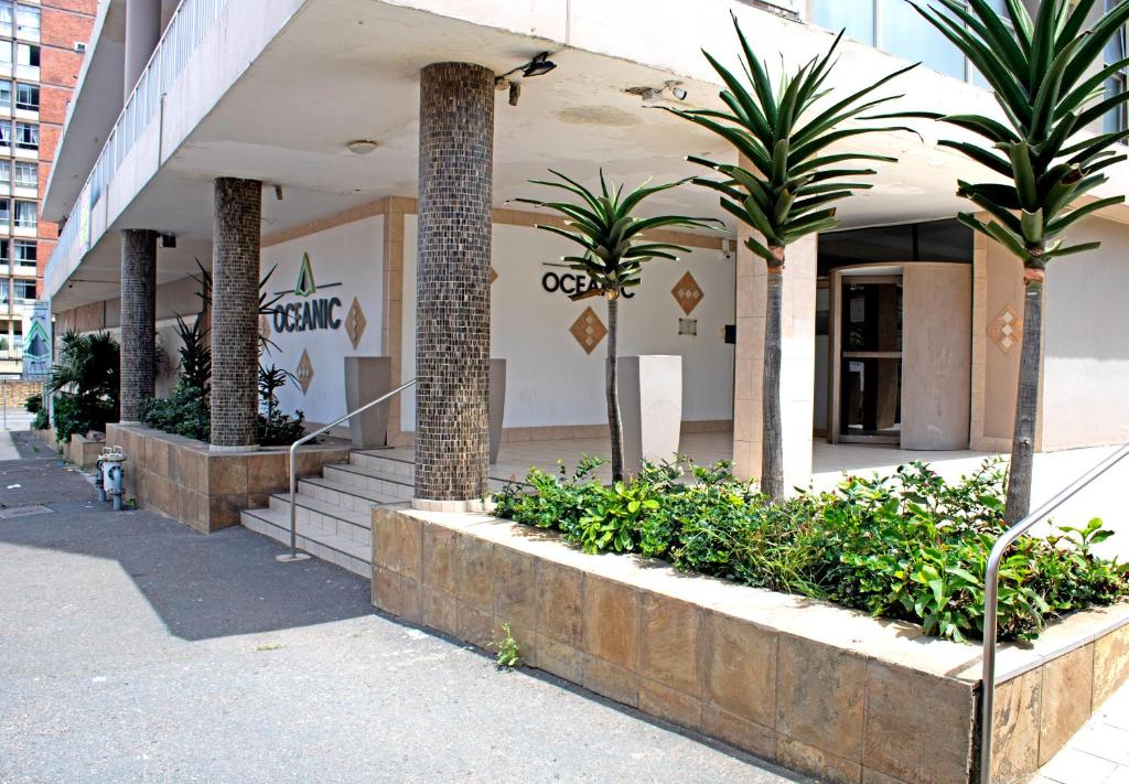un bâtiment avec des palmiers et des plantes devant lui dans l'établissement 56 Oceanic Holiday Apartment, à Durban