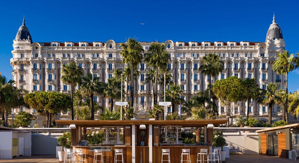 a large building with palm trees in front of it at Regent Carlton Cannes in Cannes