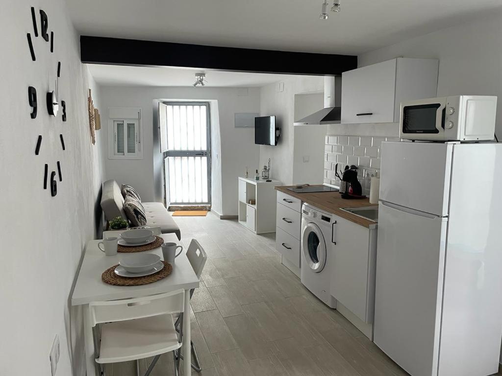 een keuken met een witte koelkast en een tafel met een wasmachine bij La Faraona in Jerez de la Frontera