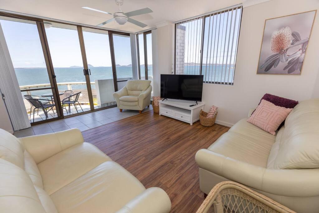 a living room with a white couch and a television at Sunrise @ the Point - Lovely 2 bdr unit with Pool in Soldiers Point