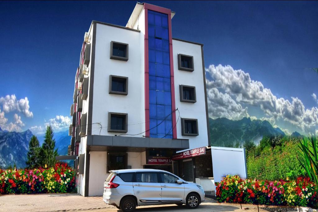 um carro estacionado em frente a um edifício com flores em Hotel Temple Sai em Shirdi