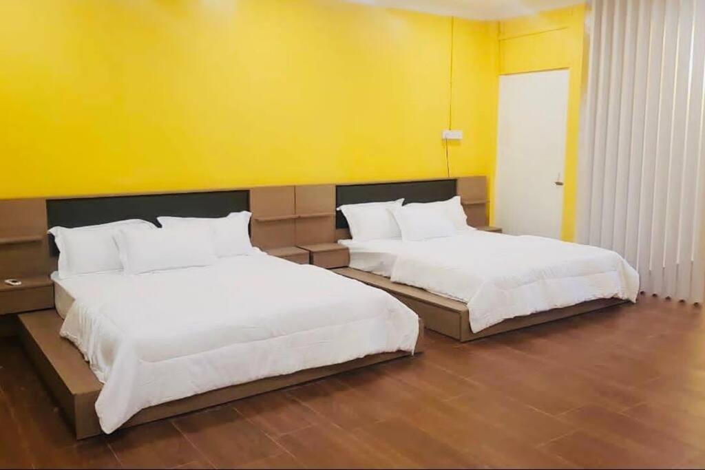 2 camas en una habitación con una pared amarilla en Irama Studio with Indoor Private Pool, en Kota Bharu
