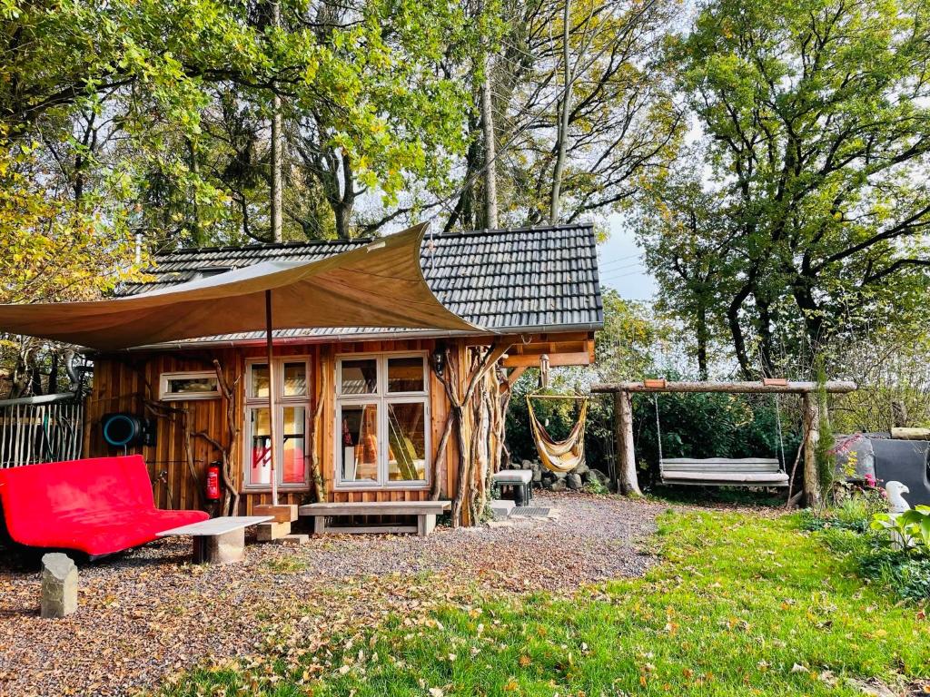 a small cabin with a red chair and a bench at Tiny House/Waldhaus - Westerwald 