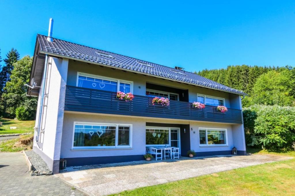 Cette maison bleue dispose de fenêtres et d'un balcon. dans l'établissement Ferienwohnung Schöne Aussicht am Rothaarsteig, à Bad Laasphe