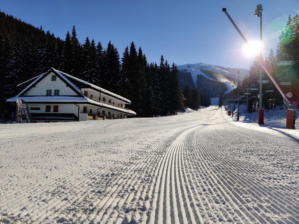 una carretera cubierta de nieve con huellas en la nieve al lado de un edificio en Apartmány Biela Púť - Jasná nr. 3 en Demanovska Dolina