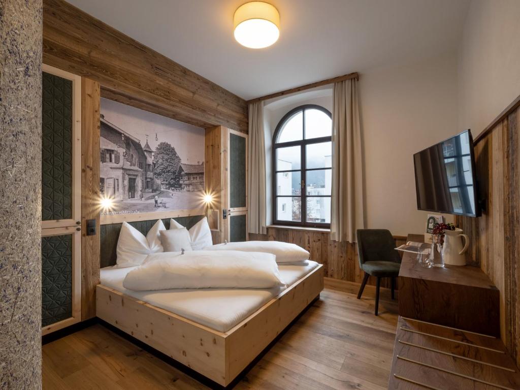 Habitación de hotel con cama y TV en Kirchenwirt Wörgl, en Wörgl