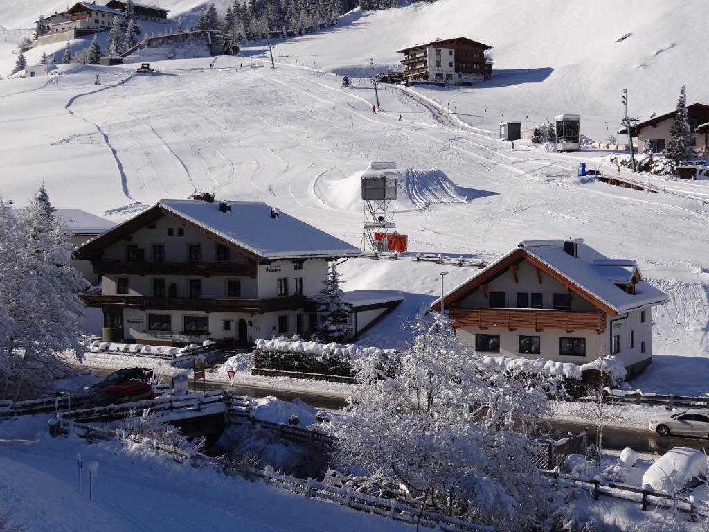 a snow covered village with buildings and a ski slope at Ferienwohnungen Hinteranger in Tux