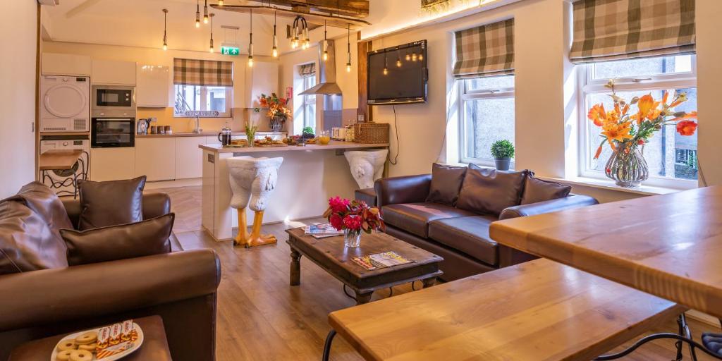 a living room with couches and a kitchen at Lakes Boutique Hostel Apartment Windermere in Windermere