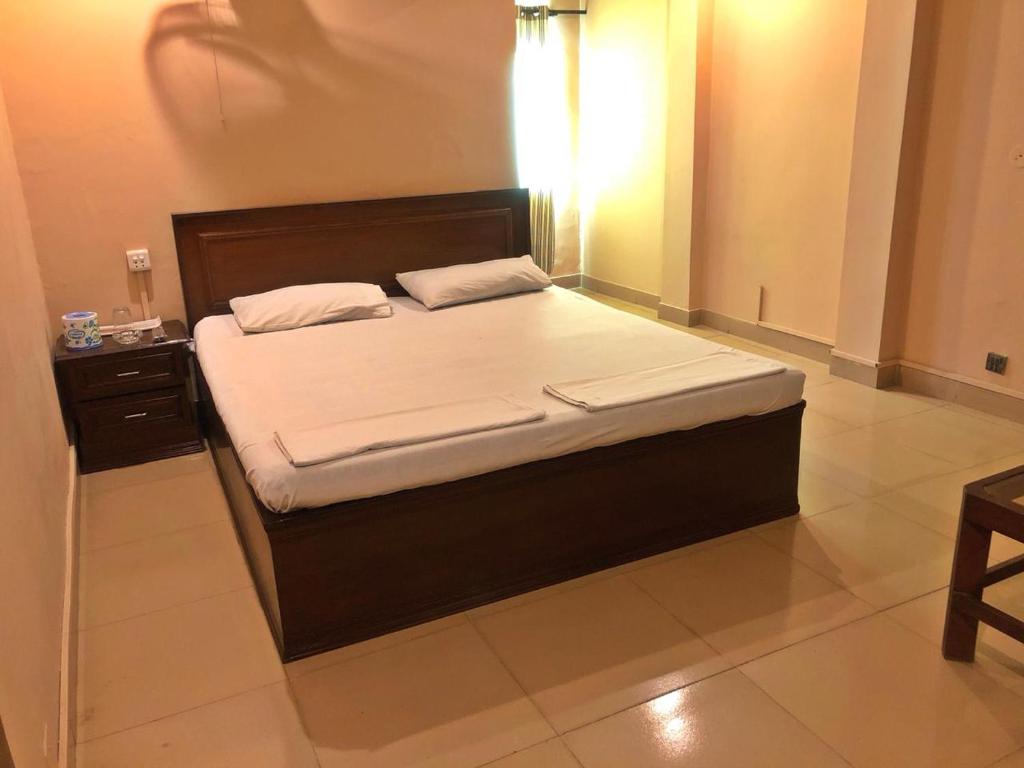 Schlafzimmer mit einem großen Bett mit einem Kopfteil aus Holz in der Unterkunft Babar House in Faisalabad