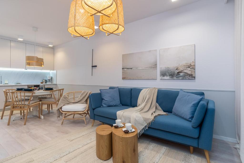 a living room with a blue couch and a table at Lux Wellness Resort & SPA Apartments by the River by Renters Prestige in Dziwnów