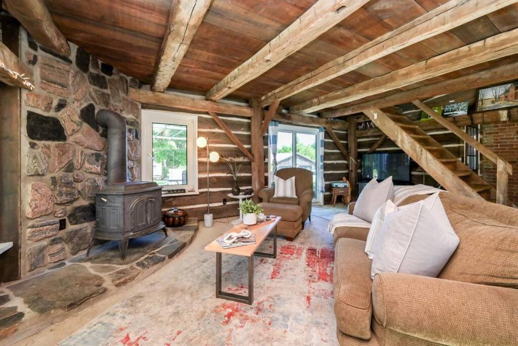 sala de estar con chimenea y pared de piedra en A charming, rustic 150 year old Carriage House, en Orangeville