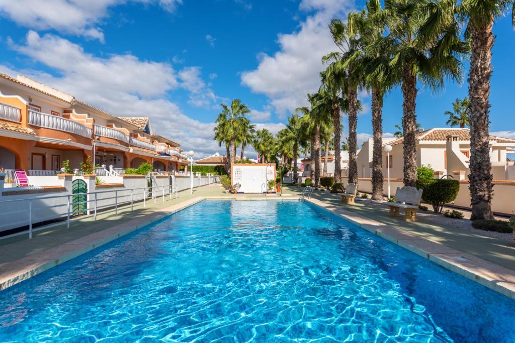 una piscina con palmeras y edificios en A beautiful 2 bedroom townhouse - Las Cerezas, en Ciudad Quesada