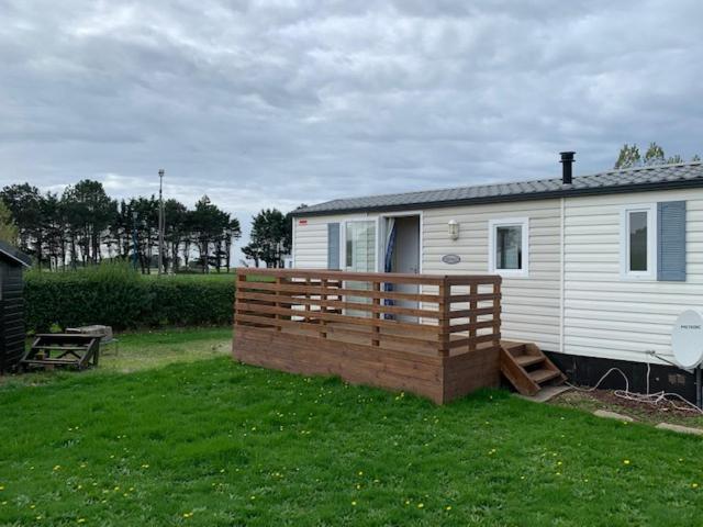 a house with a wooden fence in a yard at Mobilhome (29) 4 pers St Martin aux Buneaux in Saint-Martin-aux-Buneaux