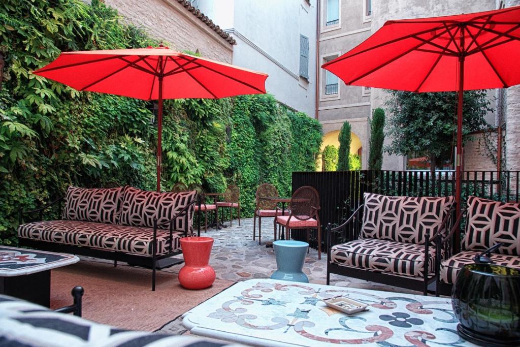 a patio with two couches and a red umbrella at Bellacorte Gentiluogo per Viaggiatori in Parma