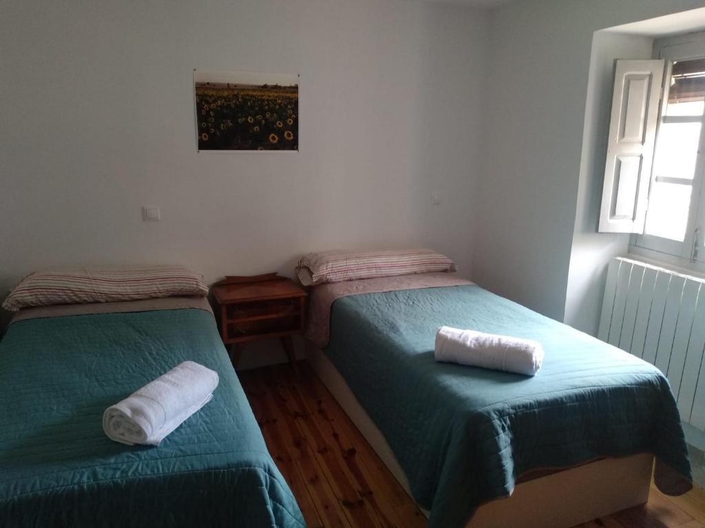 two beds in a room with green sheets and towels at La Casa del Obispo in Caleruega