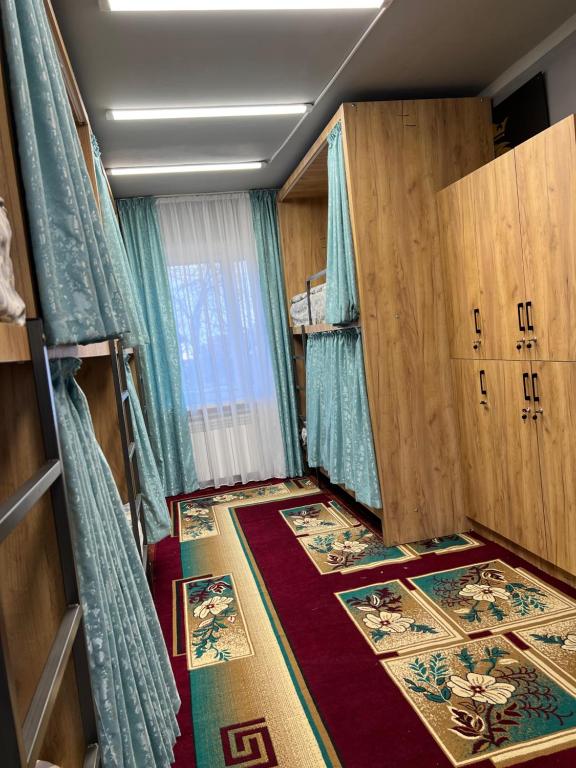Kleines Zimmer mit Holzschränken und Teppichen in der Unterkunft Hostel Edem Bishkek in Tokolʼdosh