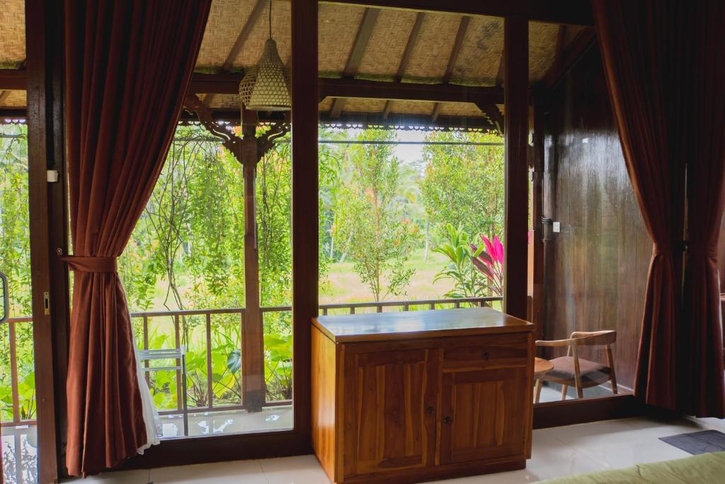 een kamer met een groot raam en een bureau in een kamer bij Mancur Guesthouse in Ubud