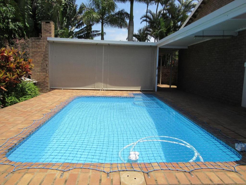 an empty swimming pool in a yard with a house at Gretna Cottage in St Lucia