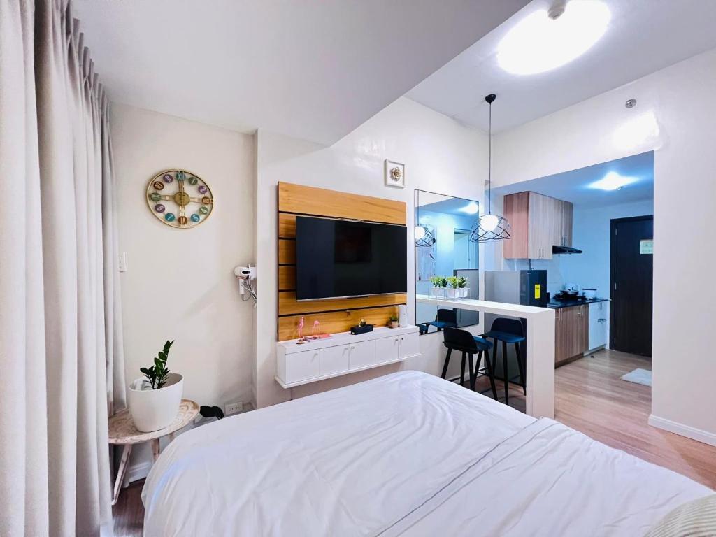 a white bedroom with a large bed and a kitchen at Studio with mountain view, near Limketkai mall in Prime Cagayan de Oro in Cagayan de Oro