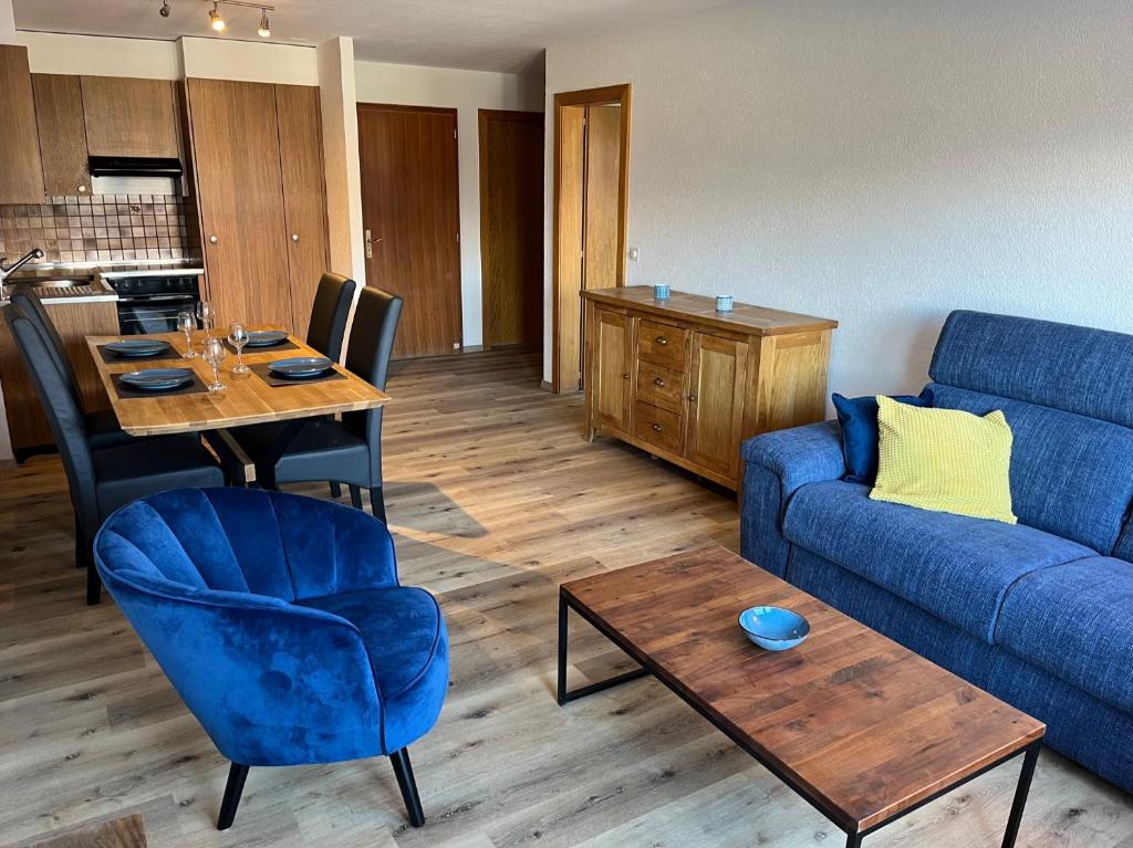 ein Wohnzimmer mit einem blauen Sofa und einem Tisch in der Unterkunft Au village de Nax, ravissant 2 pièces et demi avec terrasse in Nax