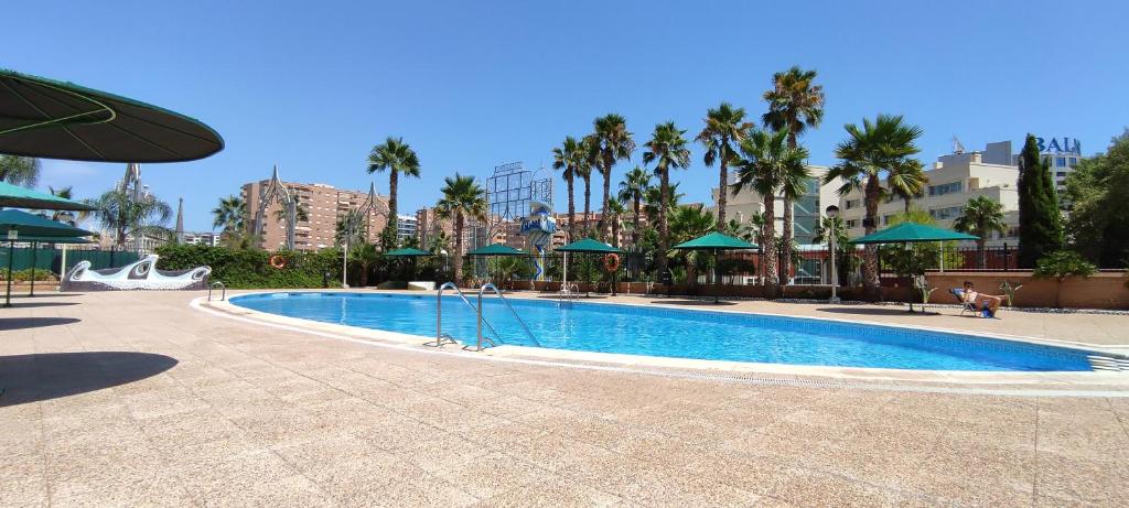una piscina en un complejo con palmeras y sombrillas en ACV - Aguamarina-2ª línea, planta 7, norte en Oropesa del Mar