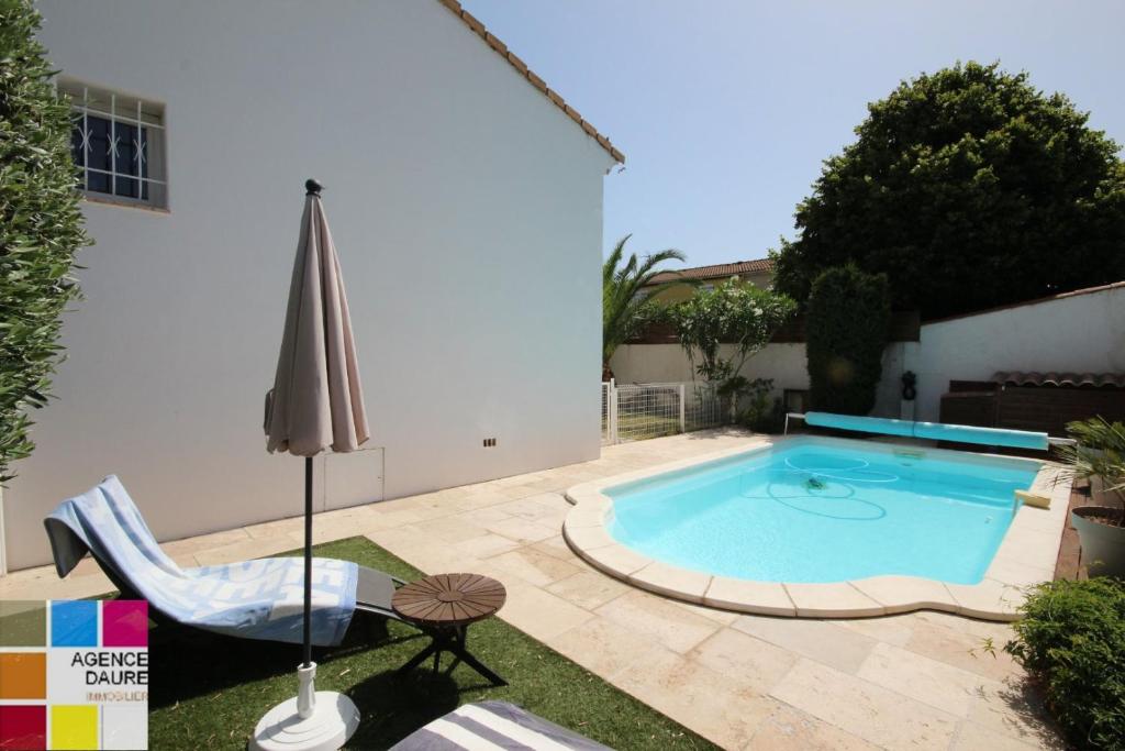 einen Pool in einem Garten mit einem Stuhl und einem Sonnenschirm in der Unterkunft Belle villa spacieuse avec piscine privée, 10 couchages,wifi, proche canal du midi et à 3 km de la mer LXPIN7 in Portiragnes