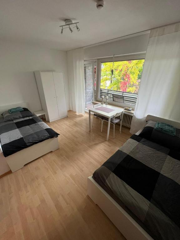1 Schlafzimmer mit 2 Betten, einem Tisch und einem Fenster in der Unterkunft Zentral gelegene Apartments am Schillerplatz in Mönchengladbach