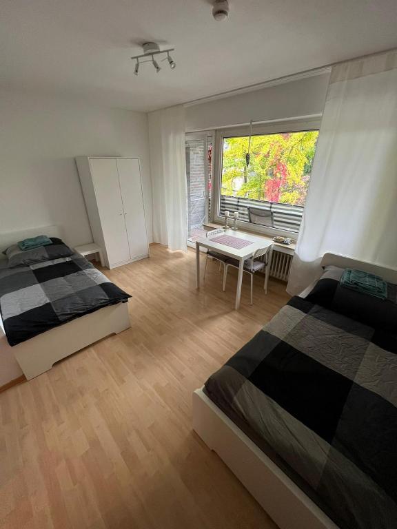 a bedroom with two beds and a table and a window at Zentral gelegene Apartments am Schillerplatz MG30 und MG31 in Mönchengladbach