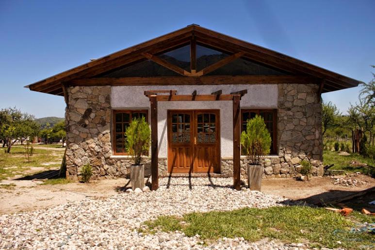 una pequeña casa de piedra con puerta de madera en Senderos del Tao en Las Rabonas