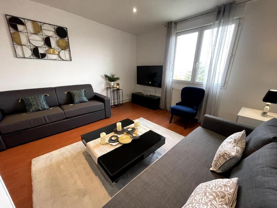 een woonkamer met een bank en een tafel bij Logement très cosy en plein centre-ville in Saint-Cyr-lʼÉcole