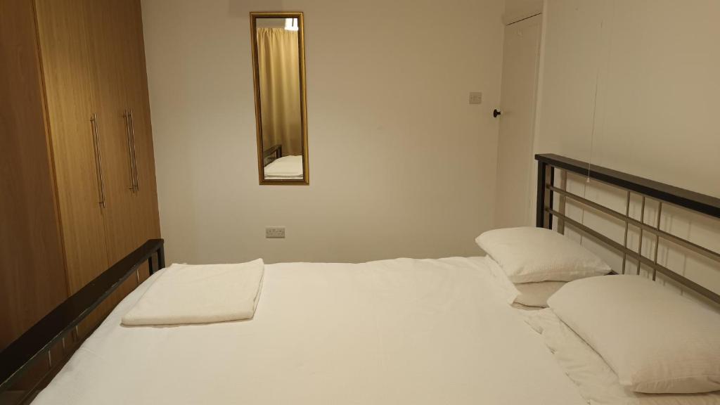 Cama blanca en habitación con espejo en Cosy relaxing 4 bed Home with 2 parking Space en Hatch End