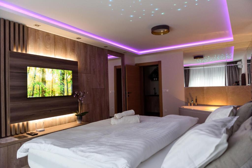 een slaapkamer met een groot wit bed met paarse verlichting bij Perla Lux apartmani in Inđija