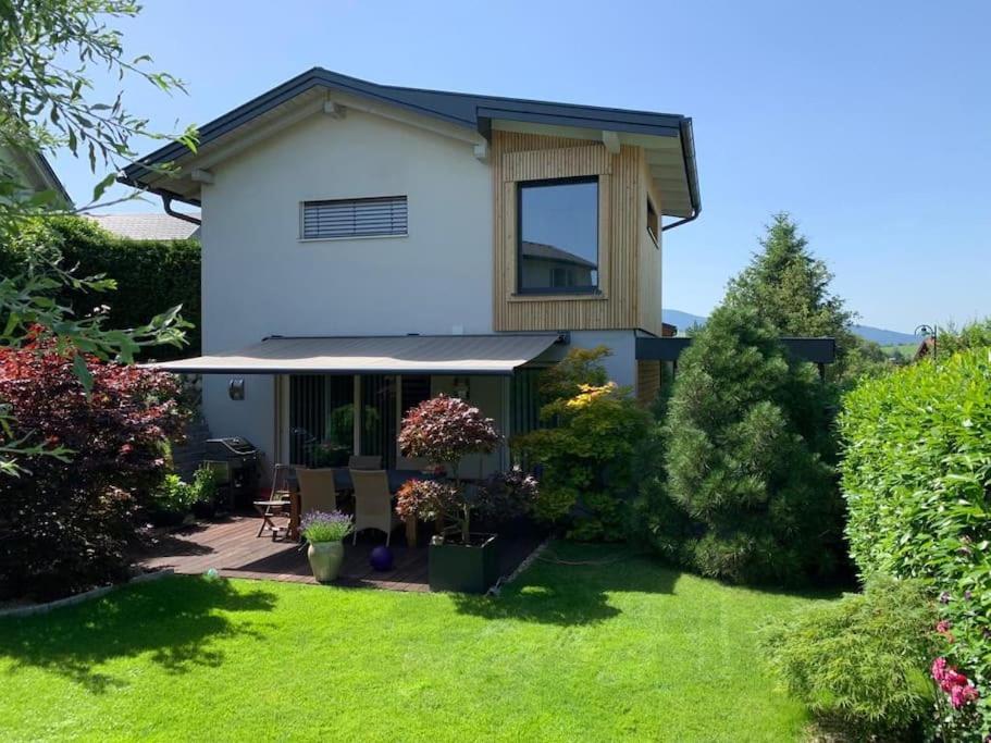 una casa blanca con un patio con césped verde en "Ferienhaus am Mondsee" mit direktem Schafbergblick im Salzkammergut bei Salzburg, en Mondsee