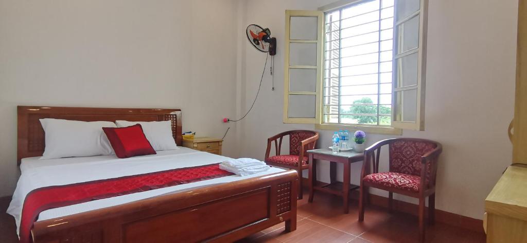 a bedroom with a bed and two chairs and a window at Thanh Hương 99 Hotel - Nội Bài in Hanoi